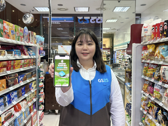 GS25 근무자가 '우리동네GS' 앱에서 진행 중인 사전예약 기획전 행사를 펼쳐 보이고 있다. GS리테일 제공